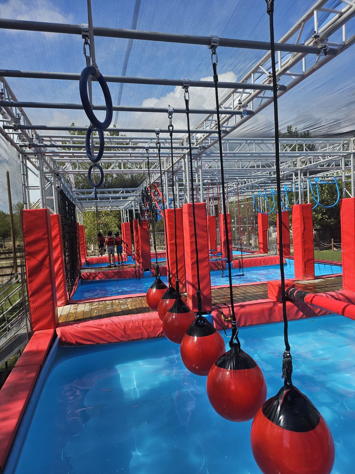 Vue générale du parc Ninja Water Crots avec obstacles rouges et piscine bleue